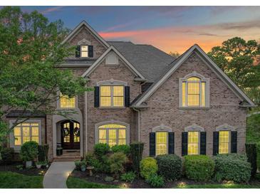 Charming brick two-story home featuring manicured landscaping, symmetrical design, and warm interior lighting peeking through the windows at 120 Shadow Ridge Ct, Statesville, NC 28677