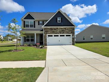 Charming two-story home featuring stone accents, a two-car garage, and well-manicured lawn at 145 Jacobs Hill Pl, Troutman, NC 28166