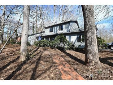 Charming gray home featuring a brick walkway, mature trees, and lush landscaping at 1793 Fairway Dr, Newton, NC 28658