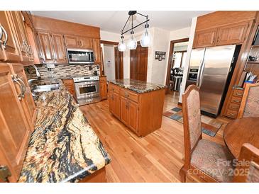 Spacious kitchen featuring wooden cabinets, stainless steel appliances, and granite countertops, perfect for cooking and entertaining at 1793 Fairway Dr, Newton, NC 28658
