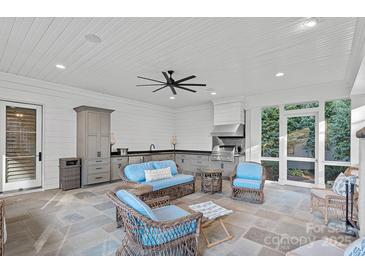 A beautiful covered outdoor kitchen features an outdoor grilling area, slate floors, and comfortable seating at 19117 Davidson Concord Rd, Davidson, NC 28036