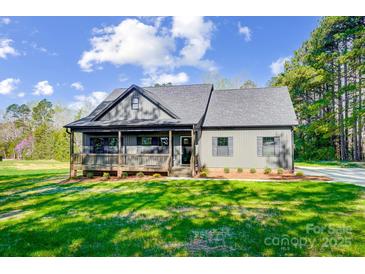 Charming home with a covered porch and manicured lawn set against a backdrop of mature trees and a blue sky at 437 Cedar Grove Rd, Clover, SC 29710