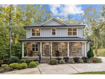 Charming two-story home with stone accents, metal roof, covered front porch, and lush landscaping at 463 Lake Wylie Rd, Belmont, NC 28012
