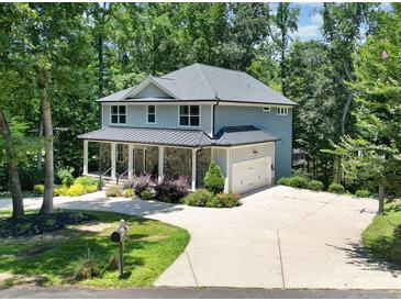Charming two-story home with a stone facade, covered porch, and lush landscaping in a wooded setting at 463 Lake Wylie Rd, Belmont, NC 28012