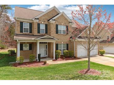 Charming two-story brick home with well-maintained landscaping, a front porch, and a two-car garage at 9391 Leyton Dr, Harrisburg, NC 28075