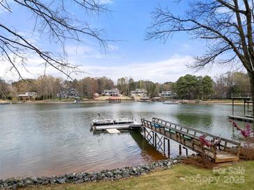 Scenic waterfront view featuring a private dock, and calm lake waters with other houses visible across the lake at 116 Cottage Grove Ln, Mooresville, NC 28117