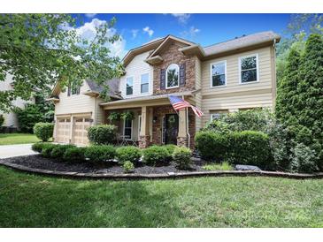 Charming two-story home with a manicured lawn, stone accents, and an American flag on the porch at 1800 Robbins Meadows Dr, Waxhaw, NC 28173