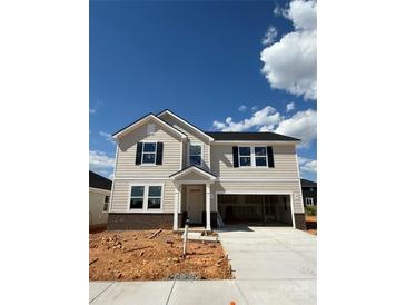 Charming two-story home with a two-car garage and neutral-colored siding, and black shutters under a bright blue sky at 317 Maidstone Dr # 57, Monroe, NC 28110