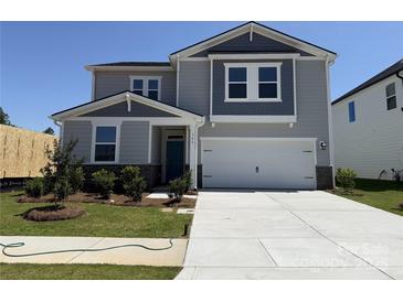 Charming two-story home with a well-manicured lawn, a driveway, and a two-car garage, with a delightful teal front door at 346 Knotty Wood Dr # 71, Monroe, NC 28110