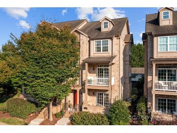 Charming townhome with brick facade, red door, and balconies under a sunny blue sky at 735 Amalfi Dr, Davidson, NC 28036