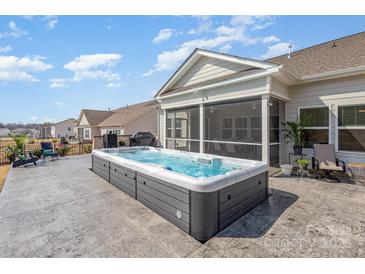 Backyard view featuring a hot tub, screened in porch, patio, and manicured backyard at 1512 Brooksland Pl, Waxhaw, NC 28173