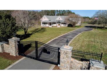 Long driveway leads to a charming country estate with stone gateposts, wrought iron gates, and an American flag at 1615 Stack Rd, Monroe, NC 28112