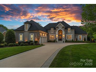 Stunning two-story home with a three-car garage and a professionally landscaped front yard under a dramatic sunset sky at 19216 Peninsula Shores Dr, Cornelius, NC 28031