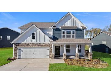 Charming two-story home with stone accents, vertical siding, covered porch, and attached two-car garage at 7024 Butternut Oak Ter, Huntersville, NC 28078