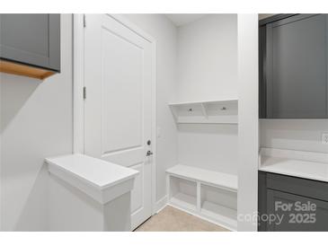 Bright mudroom with convenient bench, coat hooks, and storage cabinets at 1132 Meander Ln, Waxhaw, NC 28173