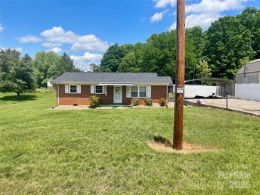 Charming brick home featuring a lush lawn, complemented by crisp white shutters and a covered front porch entrance at 1802 Young Dr, Conover, NC 28613