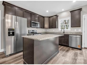 Gourmet kitchen features stainless appliances, dark wood cabinets, granite counters, and new luxury vinyl plank flooring at 1313 Gidney St, Shelby, NC 28150