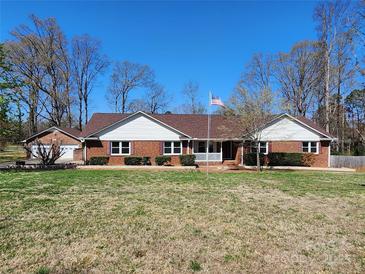 Charming single-story brick home with a well-maintained lawn and an American flag flying out front at 1301 Huckleberry Dr, Lincolnton, NC 28092