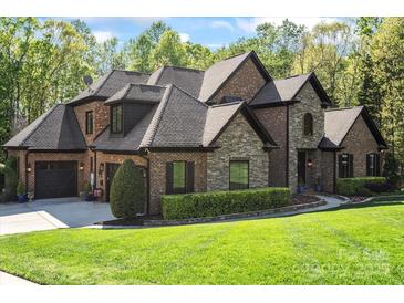 Elegant brick and stone home with a lush green lawn and mature landscaping at 1614 Shimron Ln, Waxhaw, NC 28173