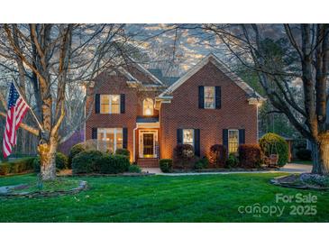 Charming two-story brick home with a well-manicured lawn, mature trees and an American flag at 4232 Belle Meade Cir, Belmont, NC 28012