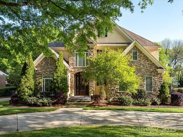 Charming stone home with a beautiful front yard and mature trees creating an inviting entrance at 5811 Old Well House Rd, Charlotte, NC 28226