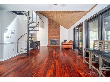 Bright living room featuring hardwood floors, a fireplace, spiral staircase, and sliding glass doors at 6199 Timberlane Ter, Hickory, NC 28601