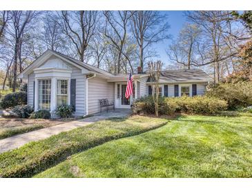 Charming single-story home with a well-manicured lawn, mature trees, and an American flag waving by the front door at 842 Mary Knoll Ct, Rock Hill, SC 29730