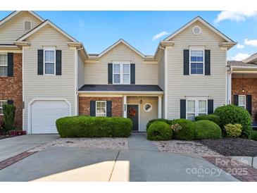 Inviting townhome featuring a well-manicured lawn, brick accents, and a convenient single-car garage at 9068 Cinnabay Dr, Charlotte, NC 28216