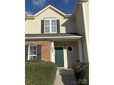 Inviting home exterior featuring a green front door, brick accents, and well-maintained landscaping at 9068 Cinnabay Dr, Charlotte, NC 28216