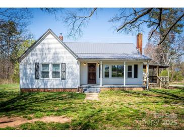 Charming one-story home featuring white siding, a metal roof, and a welcoming front porch at 260 Penninger Dr, Woodleaf, NC 27054