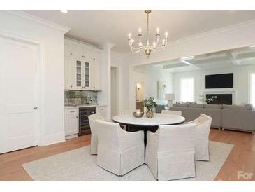 Bright dining area with modern chandelier, built-in bar and view into large living room at 3119 Knowlton Ln, Charlotte, NC 28205