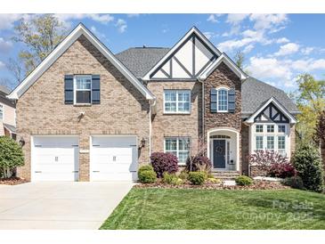 Charming two-story brick home with a two-car garage, manicured lawn, and beautiful landscaping at 717 Barossa Valley Nw Dr, Concord, NC 28027