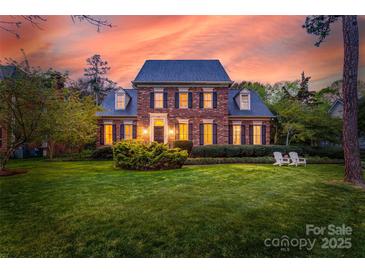 Stately brick home with manicured lawn and two chairs on the front lawn at sunset at 7700 Red Oak Ln, Charlotte, NC 28226