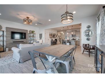 Open-concept living room and dining area with a decorative wall and modern light fixtures at 11120 Pagebrook Ln, Charlotte, NC 28214