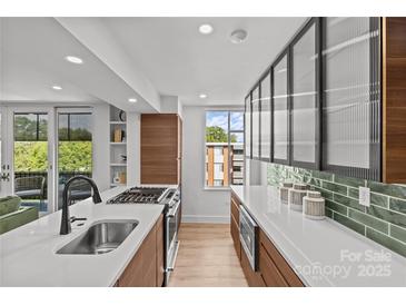 Open kitchen design with stainless steel appliances, island with seating, and hardwood floors at 1300 Queens Rd # 408, Charlotte, NC 28207