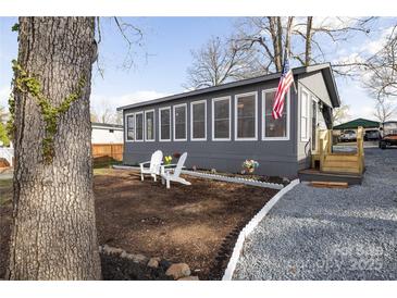 Charming gray house with a cozy front yard featuring white Adirondack chairs and a flag at 167 Holly Harbor Trl # 169/170, Mount Gilead, NC 27306
