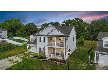 Charming two-story home with a double porch, manicured lawn, and colorful flower beds at 2019 Taylorcrest Dr, Fort Mill, SC 29715