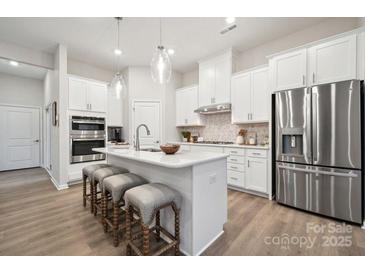 Bright kitchen with stainless steel appliances, white cabinets, and center island with bar stool seating at 8642 Miles Gap Rd, Indian Land, SC 29707