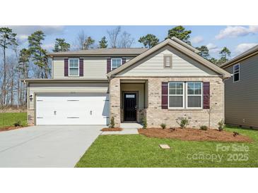 Charming two-story home featuring a brick facade, two car garage, and manicured lawn at 2581 Blue Sky Meadows Dr, Monroe, NC 28110