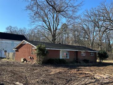 Red brick home with a dark roof and mature trees in the front yard on a sunny day at 5226 Indian Trail Fairview Rd, Indian Trail, NC 28079