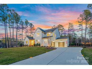 Stunning two-story home with a three-car garage, lush green lawn, and a beautifully colored sky at dusk at 6398 Chimney Bluff Rd, Lancaster, SC 29720