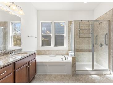 Bright bathroom featuring a soaking tub, glass shower, and granite vanity at 11037 Thornbeck Ln, Midland, NC 28107