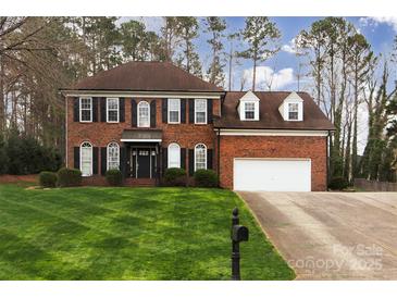 Traditional brick home with a well-maintained lawn and two-car garage with an inviting covered front entrance at 10928 Jardin Way, Charlotte, NC 28215