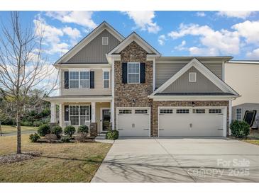 Inviting two-story home featuring a stone facade and a spacious three-car garage and manicured lawn at 276 Annatto Way, Tega Cay, SC 29708