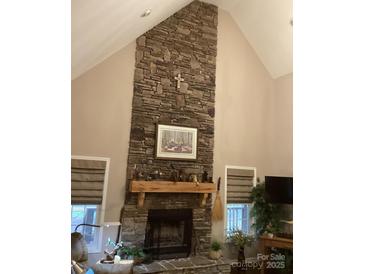 Living area with a floor-to-ceiling stone fireplace and a decorative wooden mantle at 7218 Alexander Farm Rd, Monroe, NC 28110