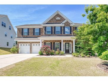 Beautiful brick home with three-car garage and well-manicured lawn on a sunny day at 9937 Travertine Trl, Davidson, NC 28036