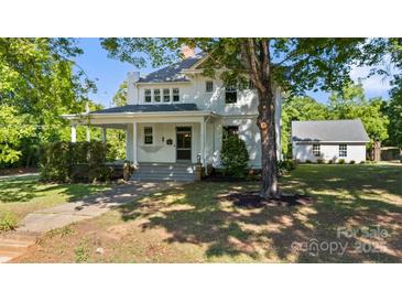 Charming two-story white home with a covered front porch and a well-maintained lawn and mature trees at 127 Charlotte St, Mooresville, NC 28115