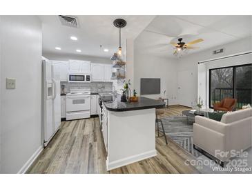 Bright, open living space featuring a modern kitchen with white appliances and an adjacent living room with a ceiling fan at 211 Heritage Blvd # 301, Fort Mill, SC 29715