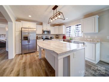 Bright kitchen featuring white cabinets, stainless steel appliances, and a large island with a marble countertop at 185 Crystal Bay Dr, Mooresville, NC 28115