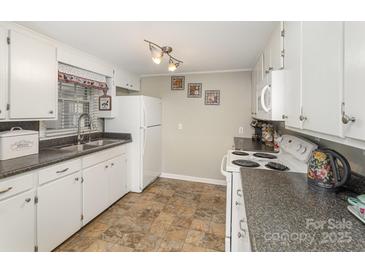 Functional kitchen with white cabinetry, laminate counters, and tile floors at 515 Burlington St, Wadesboro, NC 28170